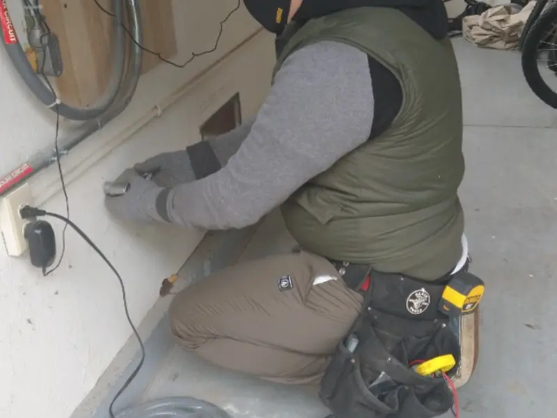 Electrician performing outlet wiring in a DeMotte garage